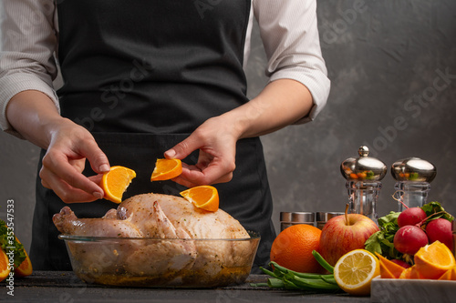 Chef cooks chicken for baking in the oven, decorates with fruits. Holidays, Christmas, New Year or a day of blessing. Menu, restaurant business, recipe book