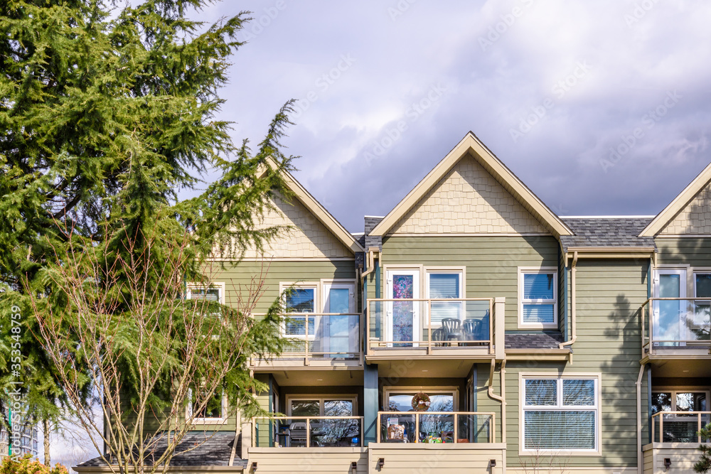 Fototapeta premium A perfect neighborhood. Houses in suburb at Summer in the north America. Top of a luxury house with nice window over blue sky.