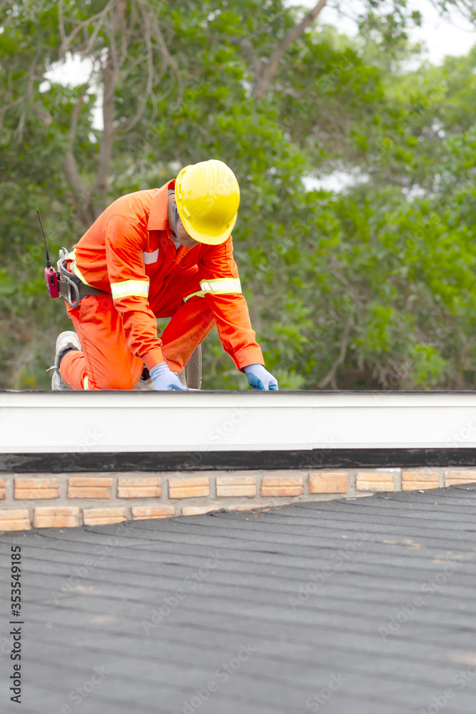 Construction worker putting the asphalt roofing (shingles) with nail gun on a large commercial apartment building development