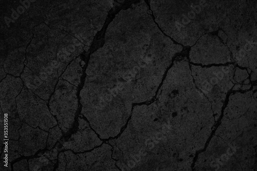 Black grunge background. Texture of cracked concrete wall. Close-up. Background with old dirty rough stone surface.