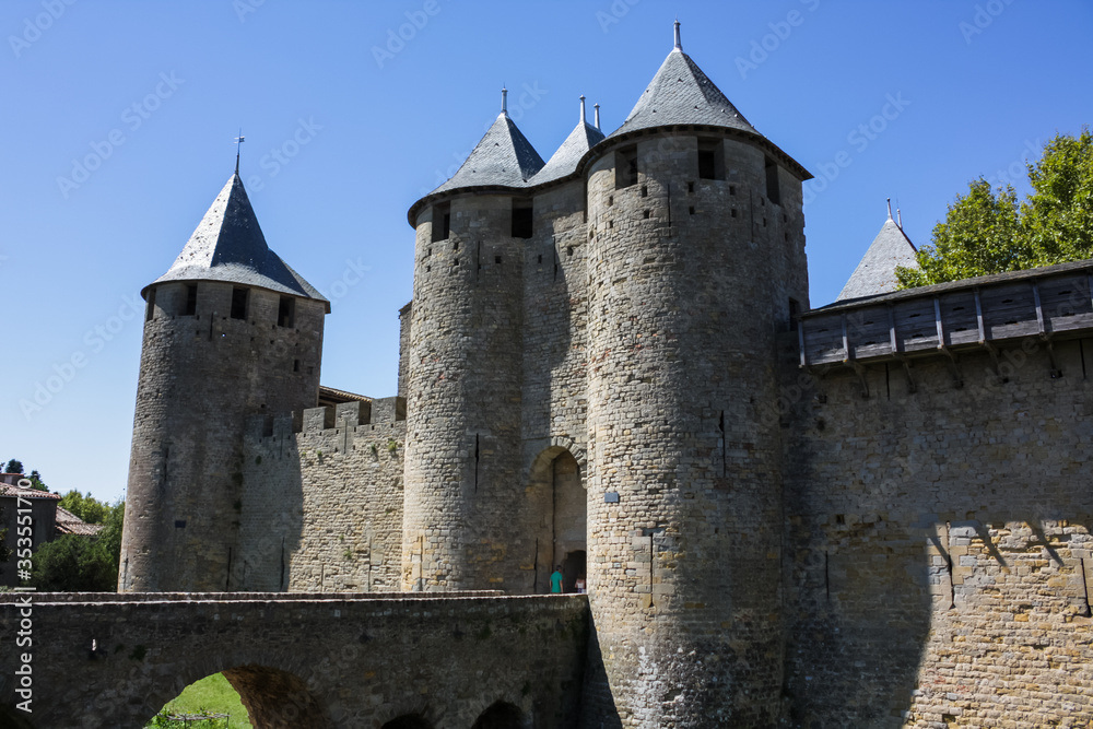 France, Carcassonne— AUGUST 28, 2014. Powerful fortifications and bastions of Carcassonne Castle. Beautiful conical blue roofs of towers. Bridge and entrance to the central fortress