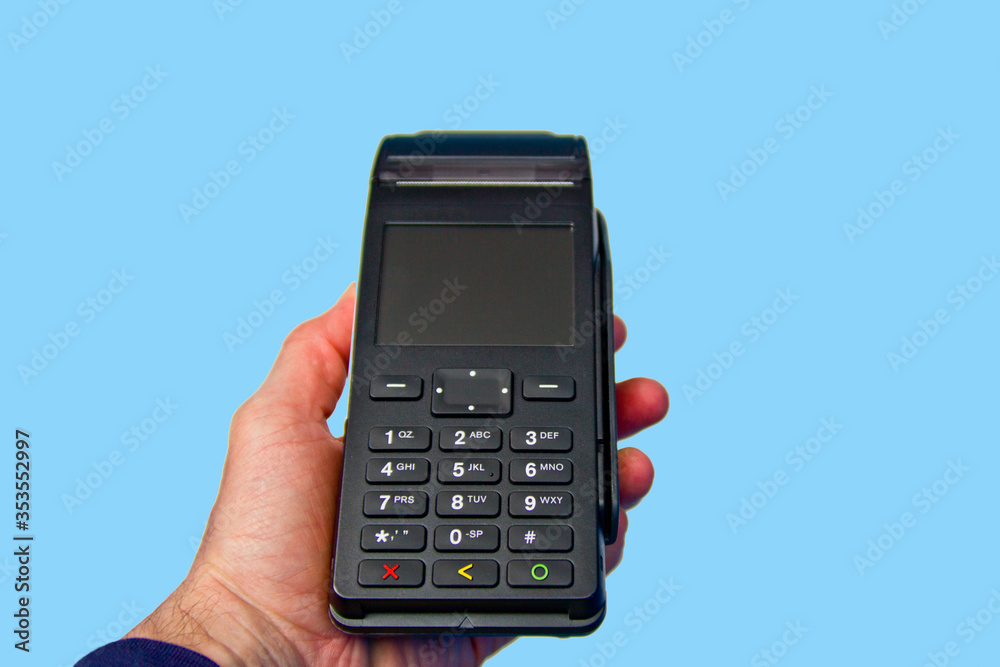 Hand is holding a credit card payment terminal on blue background. Hand is holding a credit card payment terminal on blue background.