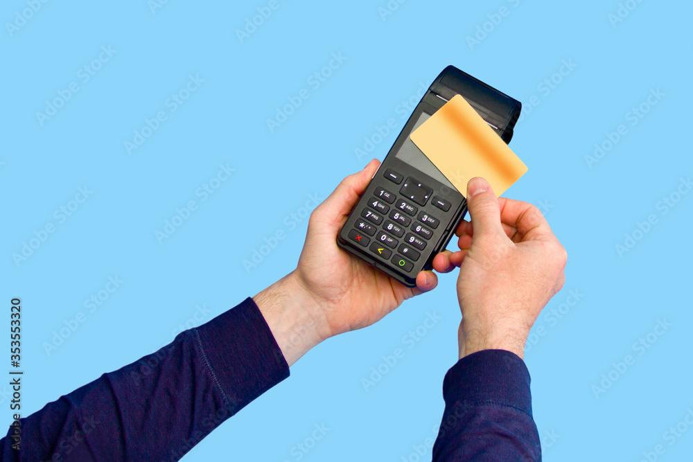 The hand holds a credit card on the payment terminal. Isolated on blue background The hand holds a credit card on the payment terminal. Isolated on blue background