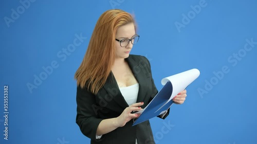 Seriously beautiful businesswoman with clipboard. Woman wearing suit and holding documents in hands. Woman is looking very seriously in the documents.