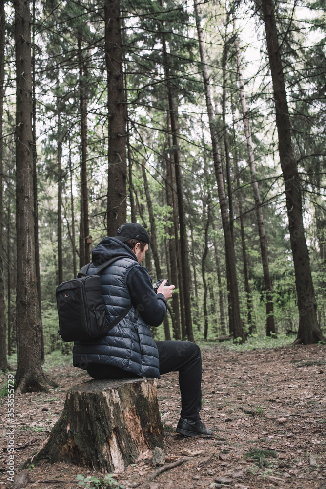 Traveler man relaxing in forest with photo camera, backpack. Travel lifestyle concept vacations outdoor. Traveler man relaxing in forest with photo camera, backpack. Travel lifestyle concept vacations outdoor.