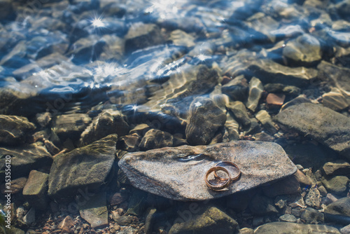 This is a stock photo features wedding rings lying in the sea on the stones. photo