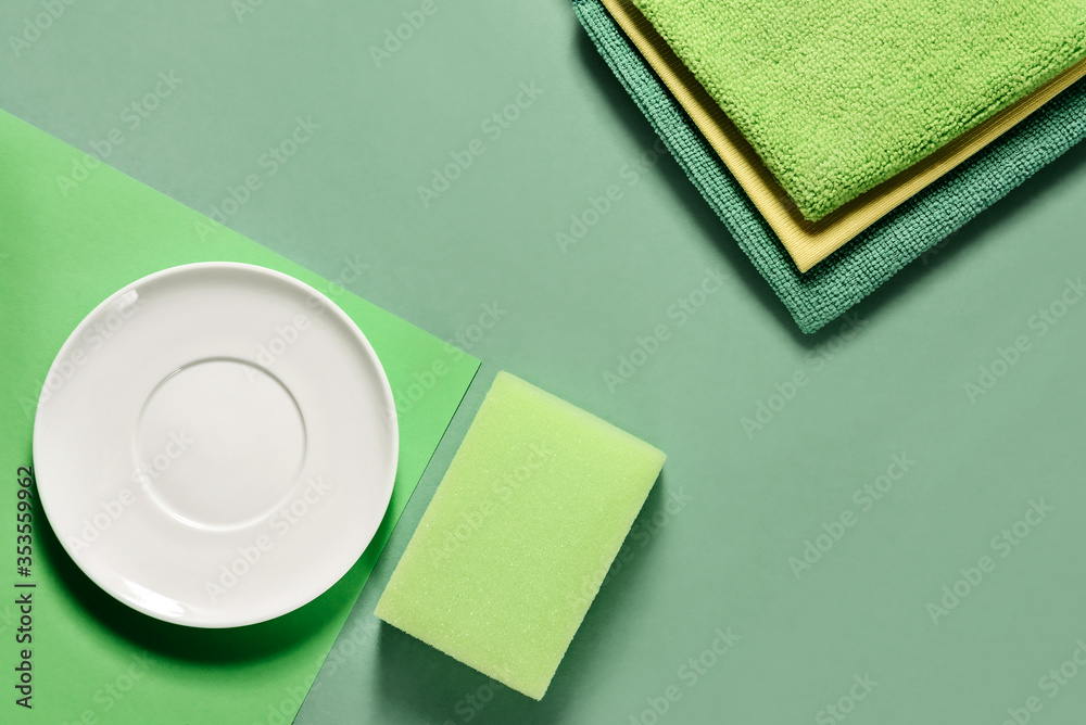 Fototapeta premium Rags, sponge for washing dishes and cleaning, a white saucer on a green background with a copy space