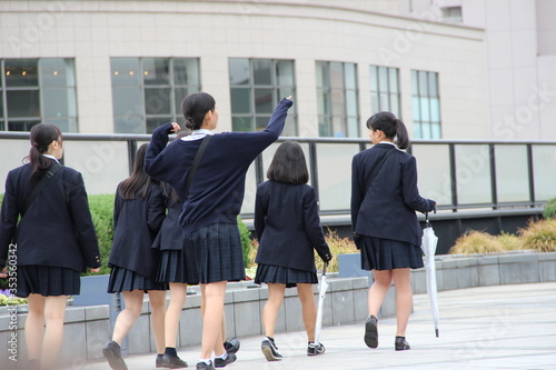 Japanische Schulmädchen mit Röcken durch die Straße laufend