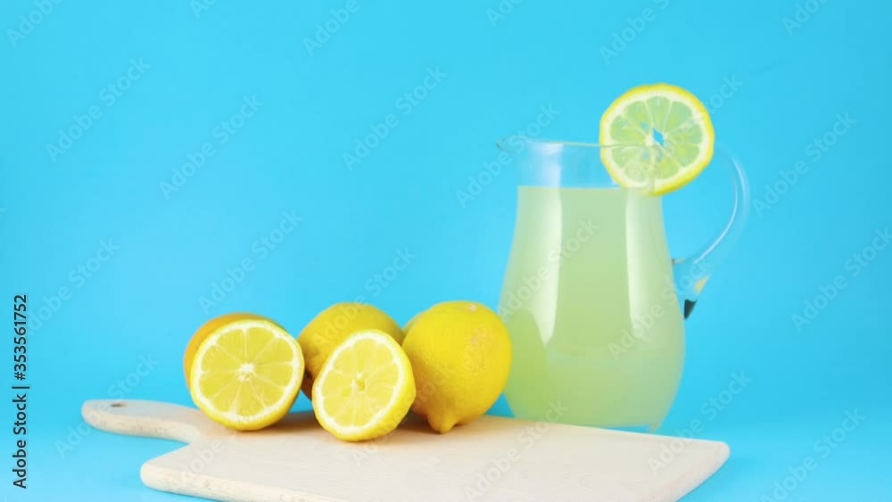 Fresh squeezed lemonade and sliced lemons on cutting board on blue background Fresh squeezed lemonade and sliced lemons on cutting board on blue background