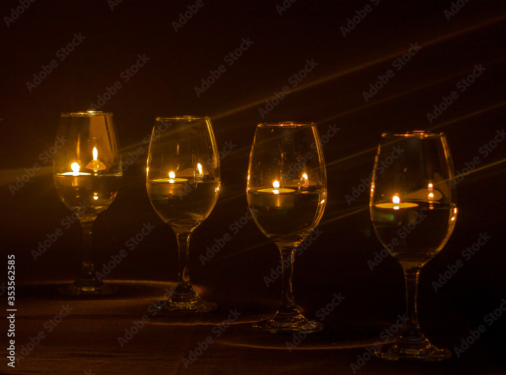 glasses at night lit by candles with black background