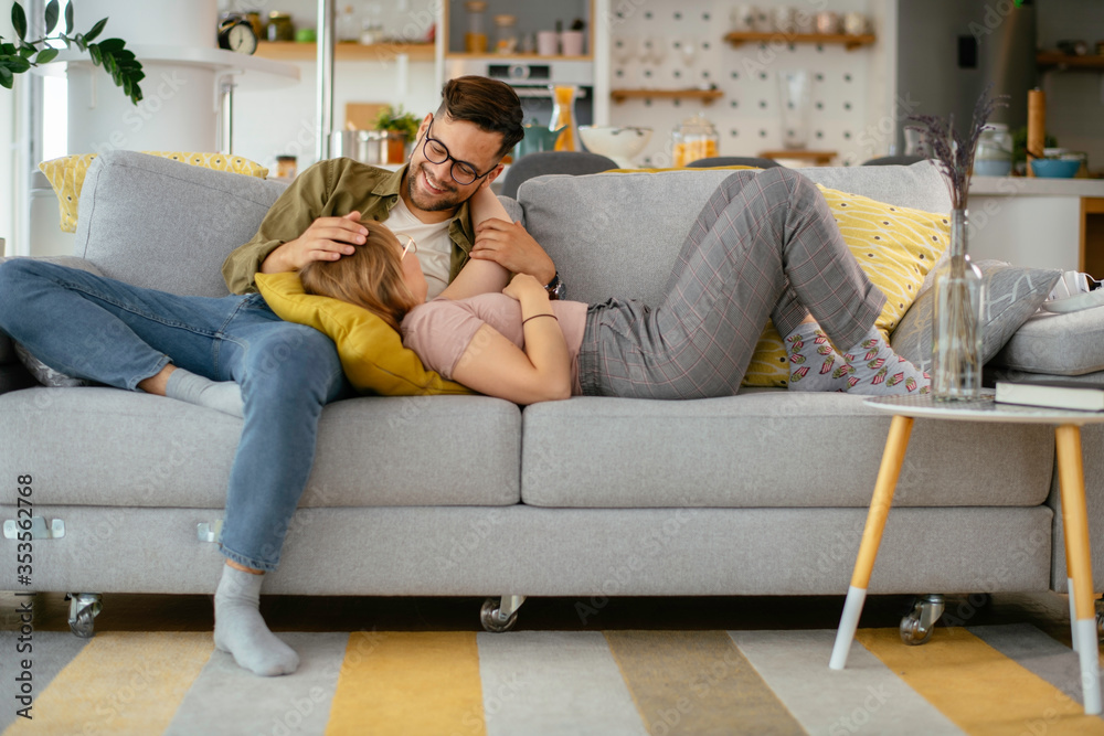 Young loving couple in sofa. Happy couple relaxing in living room.	
