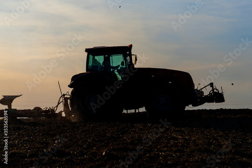 Tractor plows the land during harvest at sunset © Siarhei