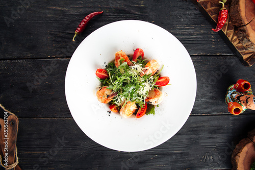 Top view on shrimp arugula salad in a white plate