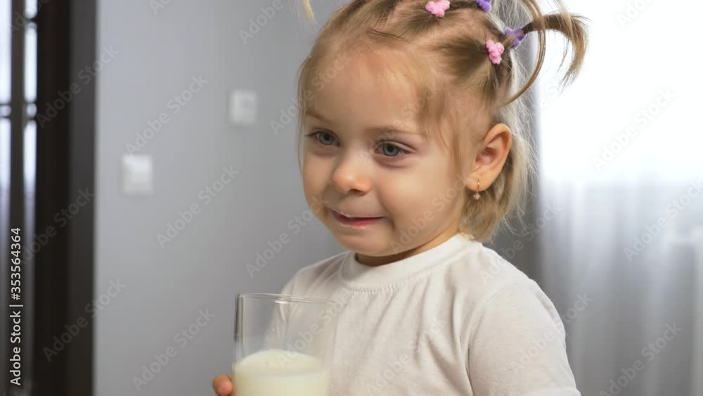 A pretty child drinks milk from a glass Cup. Organic healthy food for children. Child's Breakfast A pretty child drinks milk from a glass Cup. Organic healthy food for children. Child's Breakfast