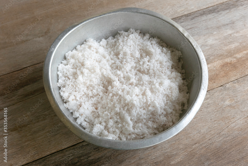 Selective focus of coconut flakes in a bowl on a wooden background. Selective focus of coconut flakes in a bowl on a wooden background.