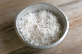 Selective focus of coconut flakes in a bowl on a wooden background.