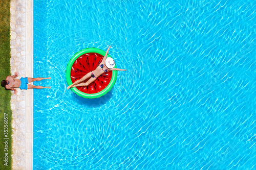 Ein Paar im Sommerurlaub hat Spaß im Swimming Pool mit Aufblasbarer Luftmatratze in Wassermelonen Form