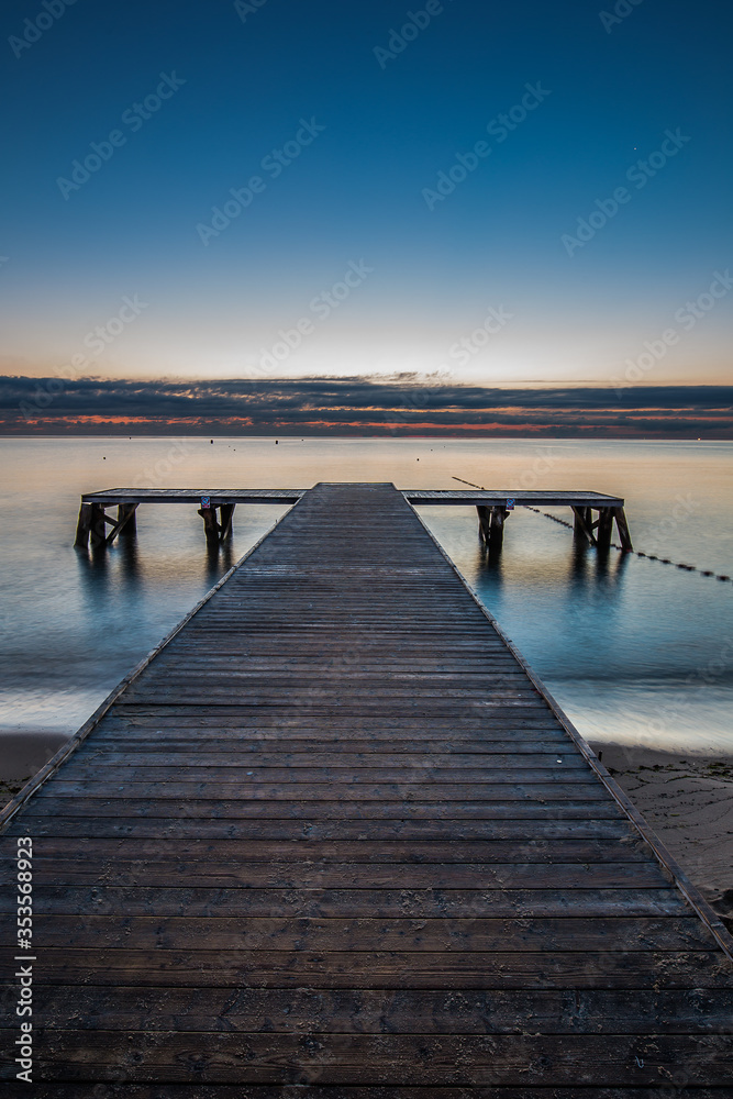 Fototapeta premium Amazing sunrise over the pier at baltic sea. Summer background