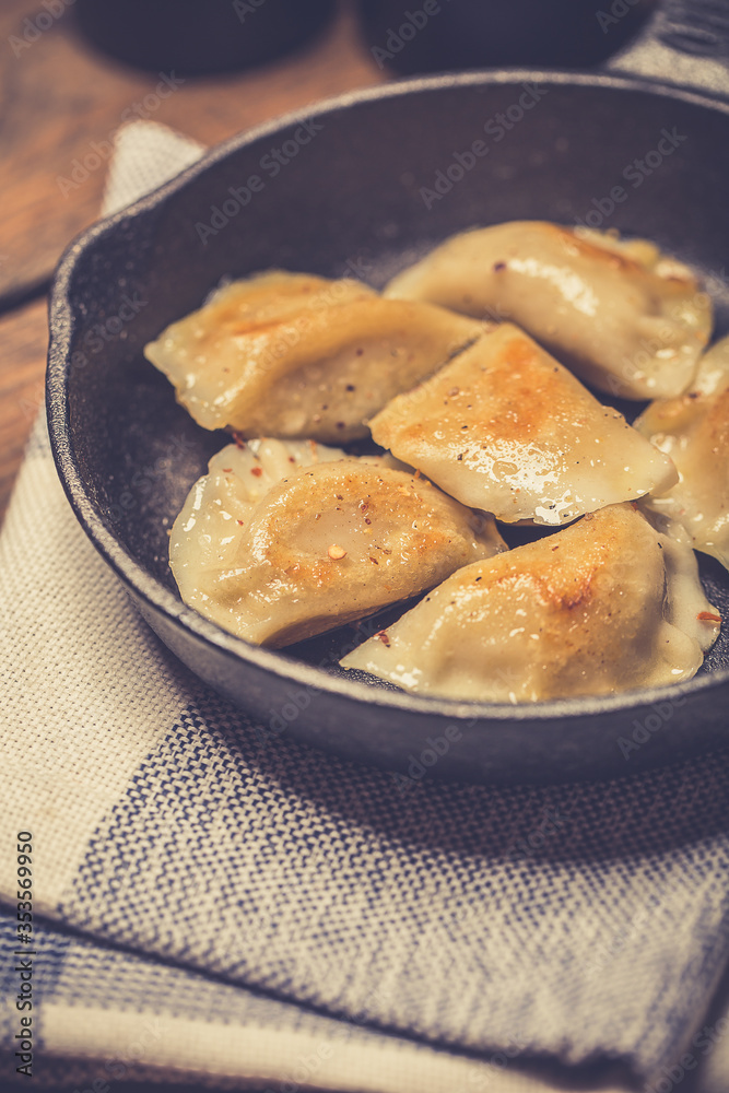 Dumplings stuffed with meat sprinkled with fresh herbs on a cast iron skillet, top view. 