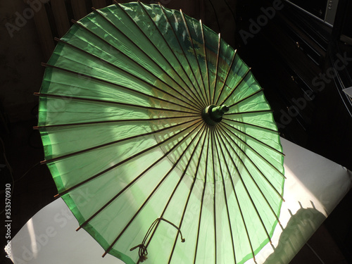 Old green sunshade with wooden ribs and pole