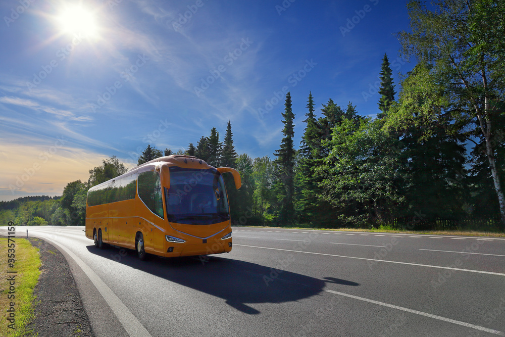 Obraz premium Yellow bus on the road at sunset carrying tourists on vacation