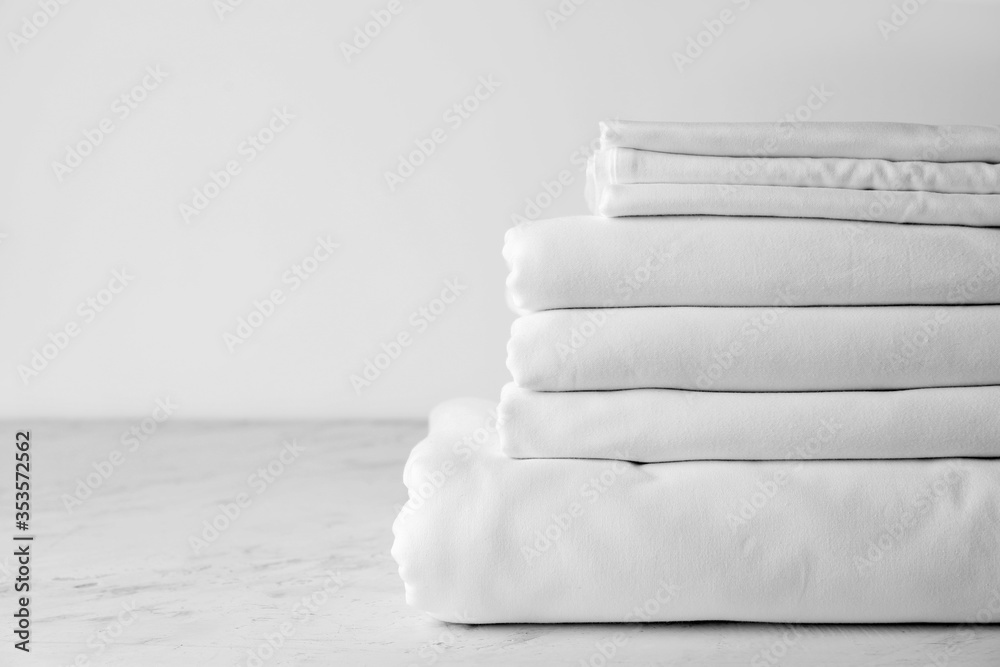 Stack of clean bed sheets on table - obrazy, fototapety, plakaty 
