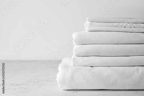Stack of clean bed sheets on table photo