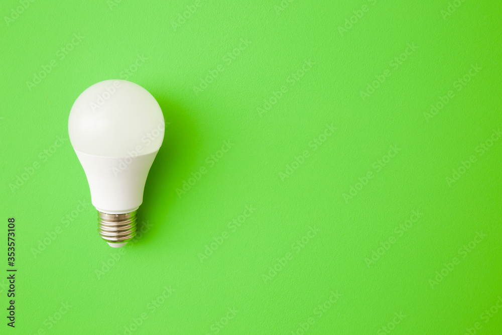 One white led light bulb on bright green table background. Closeup. Energy saving. Empty place for text or logo. Top down view. - obrazy, fototapety, plakaty 
