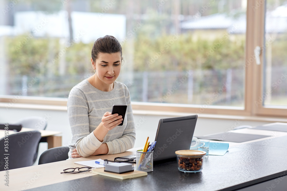 remote job, technology and people concept - young woman with smartphone and laptop computer at home office sitting at kitchen table remote job, technology and people concept - young woman with smartphone and laptop computer at home office sitting at kitchen table