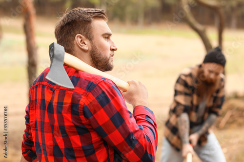 Handsome lumberjacks cutting down trees in forest © Pixel-Shot