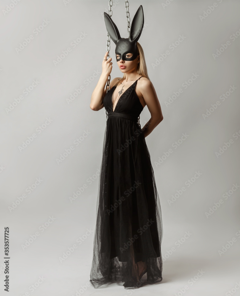 Beautiful blonde in a rabbit mask in a sexy evening dress on a white background with a metal chain Beautiful blonde in a rabbit mask in a sexy evening dress on a white background with a metal chain