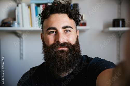 Portrait of friendly blogger smiling bearded hipster man taking a selfie in lockdown from Coronavirus, Covid-19 - Concept of video call teacher job in interview call recording vlog webinar with webcam