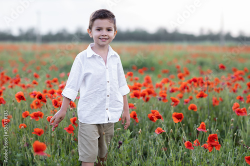 Boy stands in a linen shirt in a field of poppies