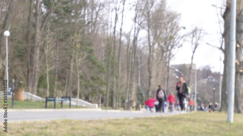 Out of focus shot of people walking in the park. People walking in a park, blur background. Out of focus shot of people walking in the park. People walking in a park, blur background.
