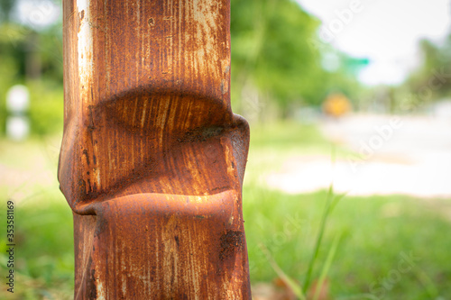 Old rusty pillar stands on a blurred natural green background.