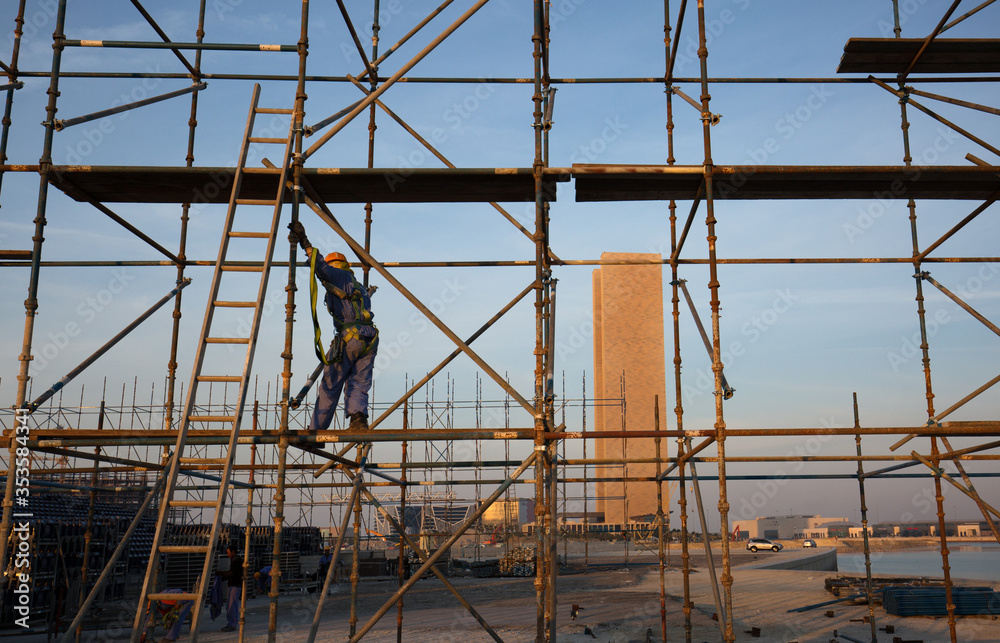 BAHRIAN BAY, BAHRAIN - FEBRUARY 05: The technician working on the top of scaffold jacks platform for construction of Grandstand near water front at Bahrain Bay on February 05, 2018. BAHRIAN BAY, BAHRAIN - FEBRUARY 05: The technician working on the top of scaffold jacks platform for construction of Grandstand near water front at Bahrain Bay on February 05, 2018.