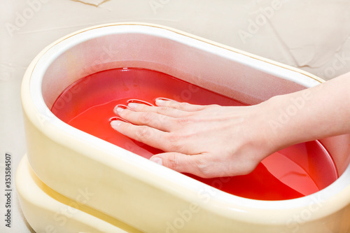 The process of paraffin therapy of a female hand is shot close up in a beauty salon.