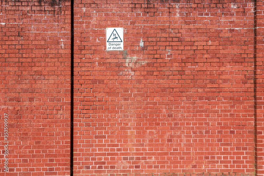 Red brick wall with a warning sign of high voltage danger Red brick wall with a warning sign of high voltage danger