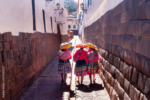 Peruvian women in typical local dresses walking down an alley in Cuzco