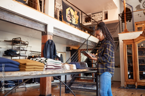 Schilderij op canvas Female Owner Of Fashion Store Using Digital Tablet To Check Stock In Clothing St