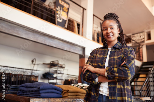 Portrait Of Smiling Female Owner Of Fashion Store Standing In Front Of Clothing Display photo