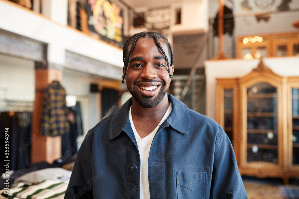 Portrait Of Smiling Male Owner Of Fashion Store Standing In Front Of Clothing Display Portrait Of Smiling Male Owner Of Fashion Store Standing In Front Of Clothing Display