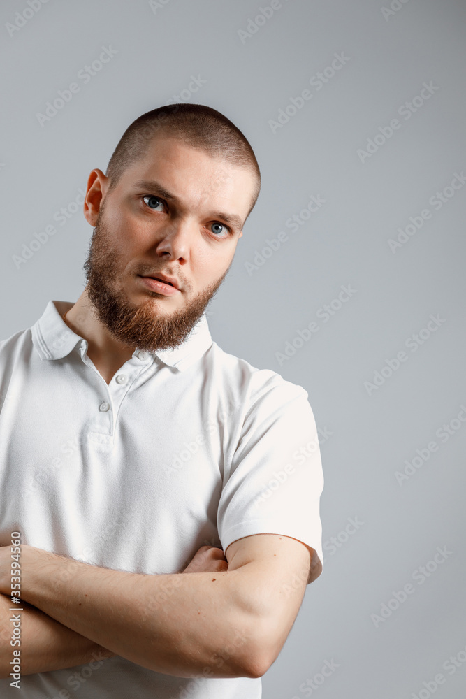 Portrait of young man in a white T-shirt seriously looking into the frame on a gray background. isolated, Copyspace Portrait of young man in a white T-shirt seriously looking into the frame on a gray background. isolated, Copyspace