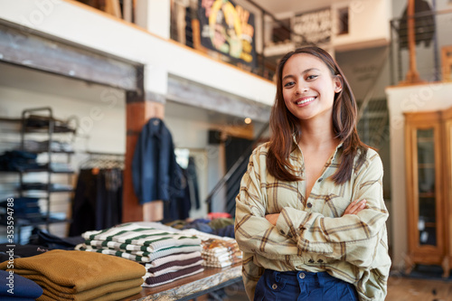 Portrait Of Smiling Female Owner Of Fashion Store Standing In Front Of Clothing Display photo