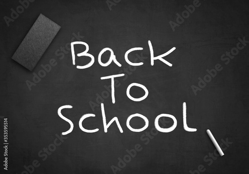 Back to school written on black chalkboard with wiper and white chalk