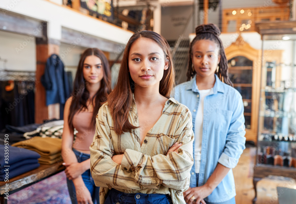 Portrait Of Multi-Cultural Female Sales Team In Fashion Store Standing In Front Of Clothing Display Portrait Of Multi-Cultural Female Sales Team In Fashion Store Standing In Front Of Clothing Display