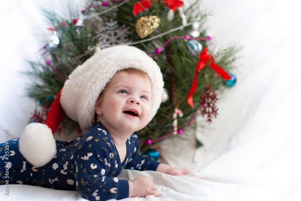 infant in santa hat near christmas tree new year infant in santa hat near christmas tree new year