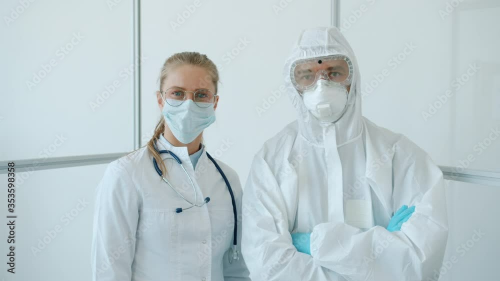 Portrait of man and woman doctors in protective uniform standing in quarantine clinic with arms crossed and looking at camera. People and medicare concept. Portrait of man and woman doctors in protective uniform standing in quarantine clinic with arms crossed and looking at camera. People and medicare concept.