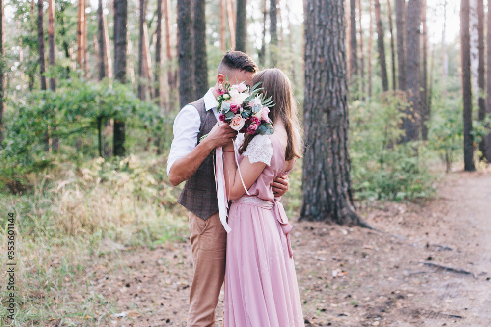 Beautiful couple at the photoshoot of love story in the forest in a rustic dress