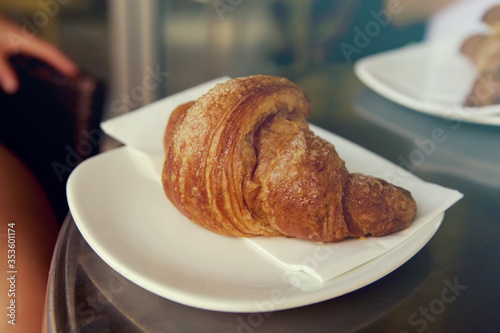 Sweet croissant served on a plate in a bar  typical italian breakfast with coffee
